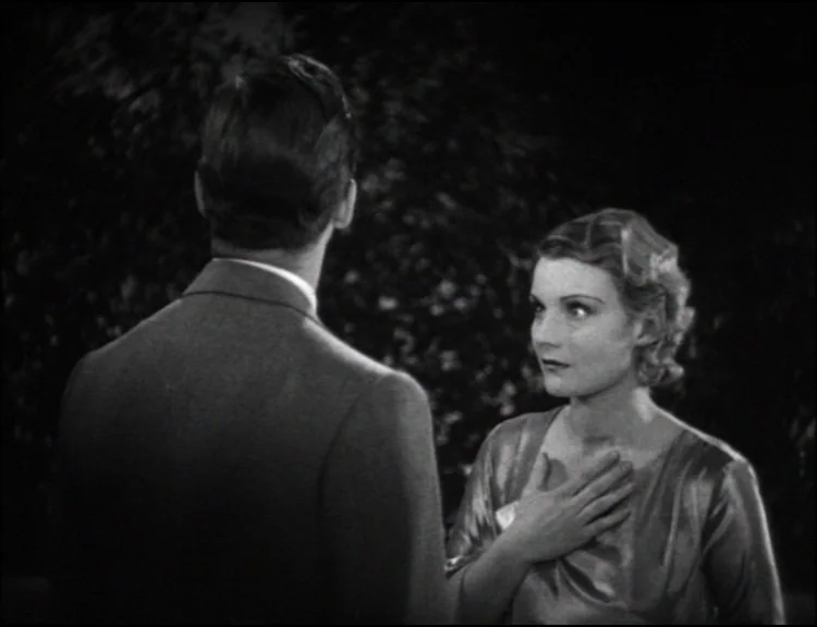 Dracula (1931) movie still: medium — An outdoor park setting at night with dark foliage visible behind the figures. A woman faces a man while…