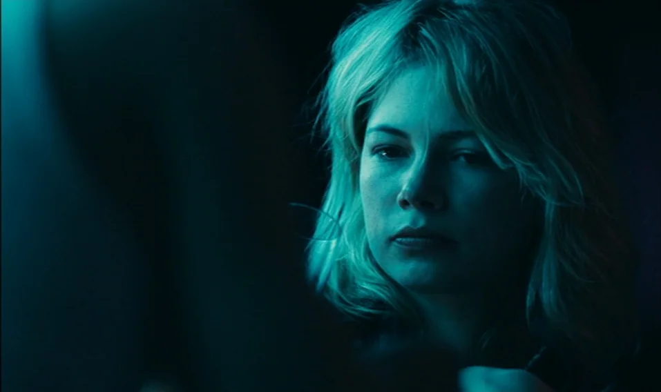 Blue Valentine (2010) movie still: closeup — A dark indoor space serves as the background, leaving the subject in deep shadow. A woman with blonde…