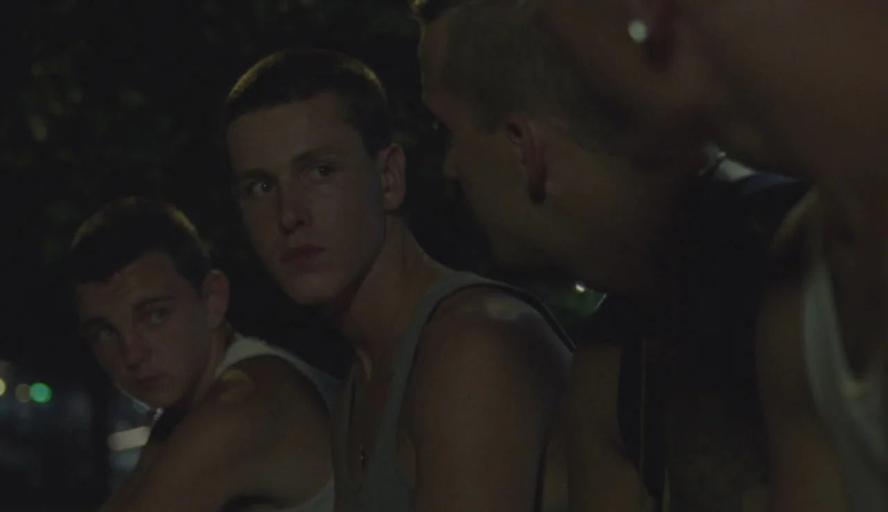 Beach Rats (2017) movie still: medium — A group of three young men sitting close together in a darkened outdoor setting. They appear to be talking…