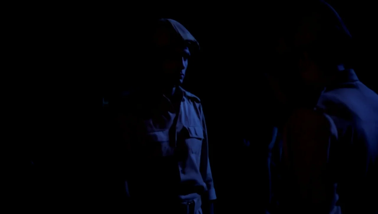 The Return of the Prodigal Son (1978) movie still: medium — Two figures wearing military-style uniforms stand together in a completely dark space.…