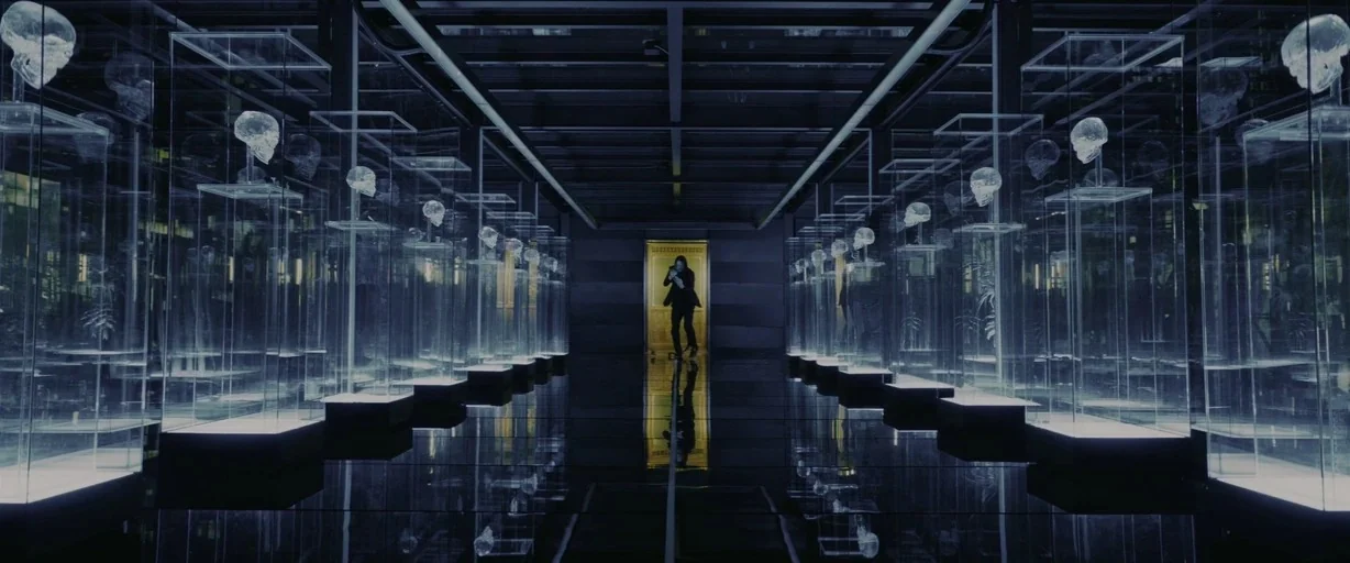 John Wick: Chapter 3 – Parabellum (2019) movie still: wide — Rows of tall, transparent rectangular pedestals holding skulls line a symmetrical,…