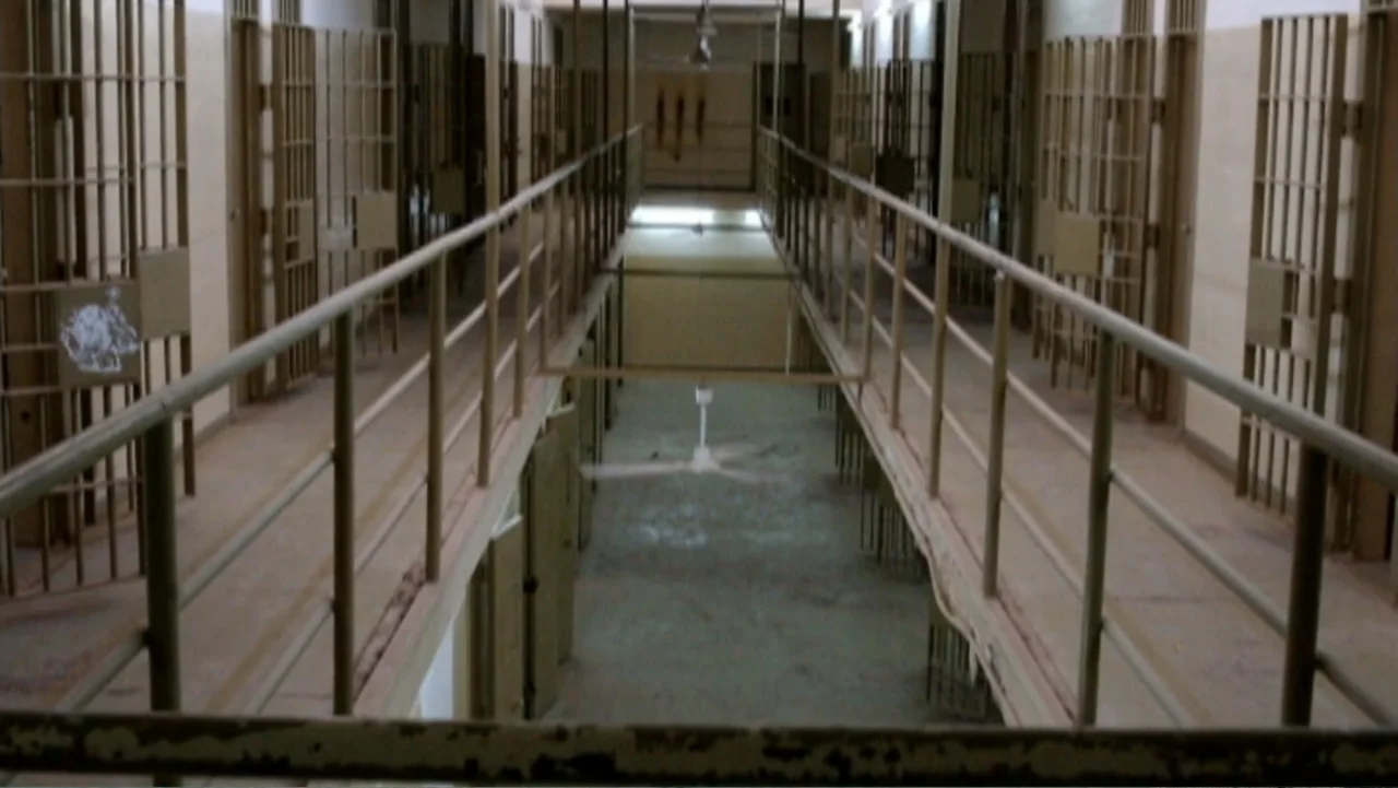 Ghosts of Abu Ghraib (2007) movie still: wide — A long, symmetrical multi-tiered prison corridor features rows of iron-barred cells on both sides.…