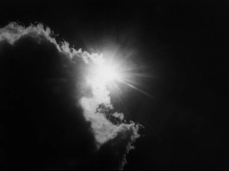 Waiting Women (1952) movie still: establishing — A vast dark sky contains a bright sun partially obscured by thick, textured clouds. The sun…