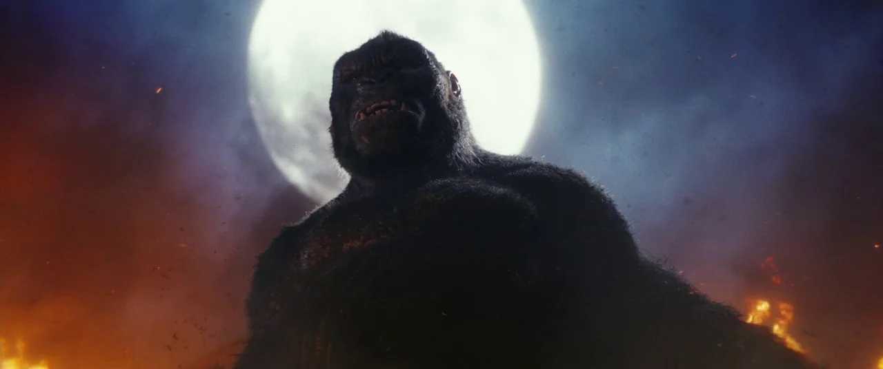 Kong: Skull Island (2017) movie still: medium — A dark, smoky battlefield filled with orange embers floats beneath a large full moon. A giant…