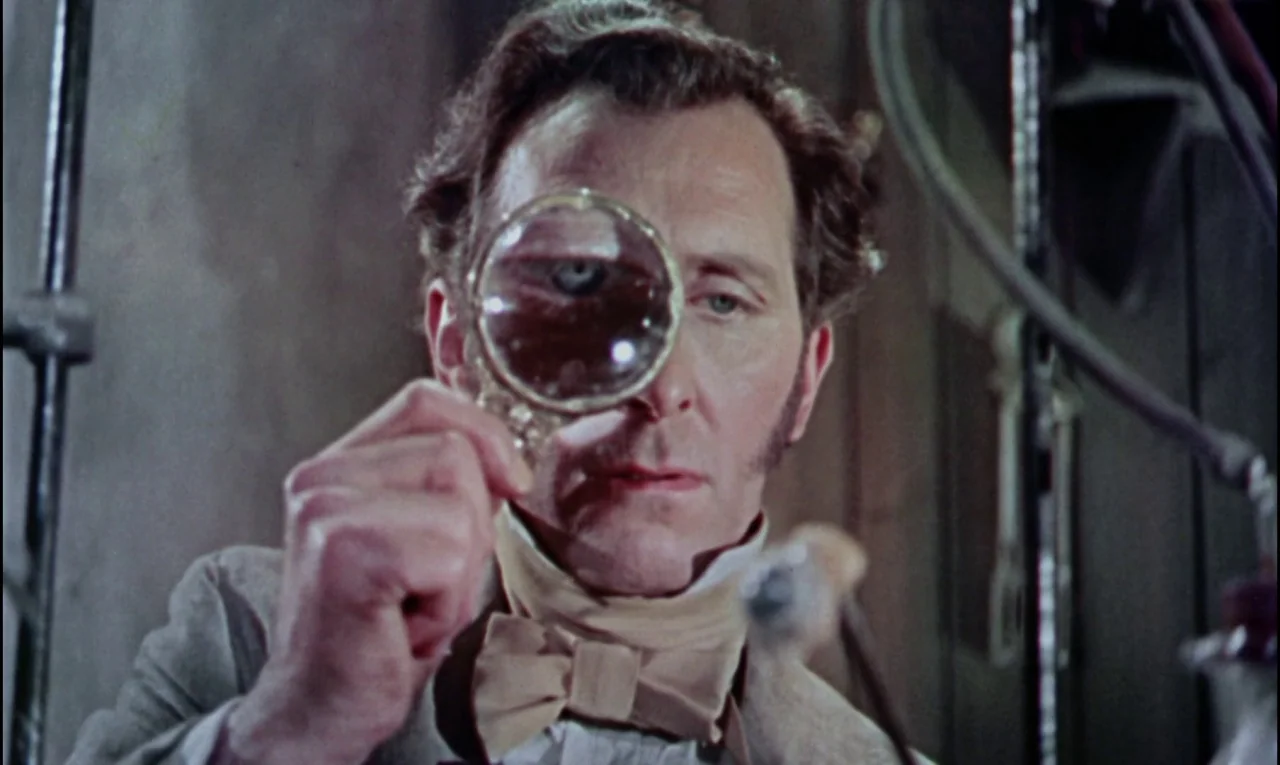 The Curse of Frankenstein (1957) movie still: closeup — A dimly lit room contains laboratory apparatus and scientific equipment in the background. A…