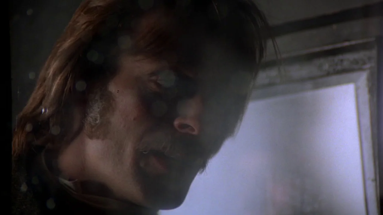 The Duellists (1977) movie still: closeup — A dimly lit interior space features a man captured in a close-up frame. He looks downward with a serious…
