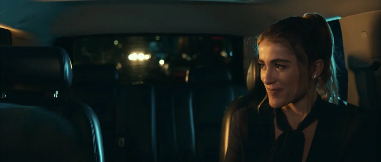 Cindy La Regia (2020) movie still: medium — A dark car interior at night shows the headrest and back seat structure. A woman sits in the passenger…