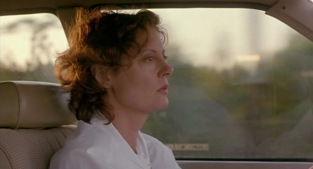 Dead Man Walking (1995) movie still: closeup — The interior of a moving car during late afternoon with a blurred landscape outside. A woman with…
