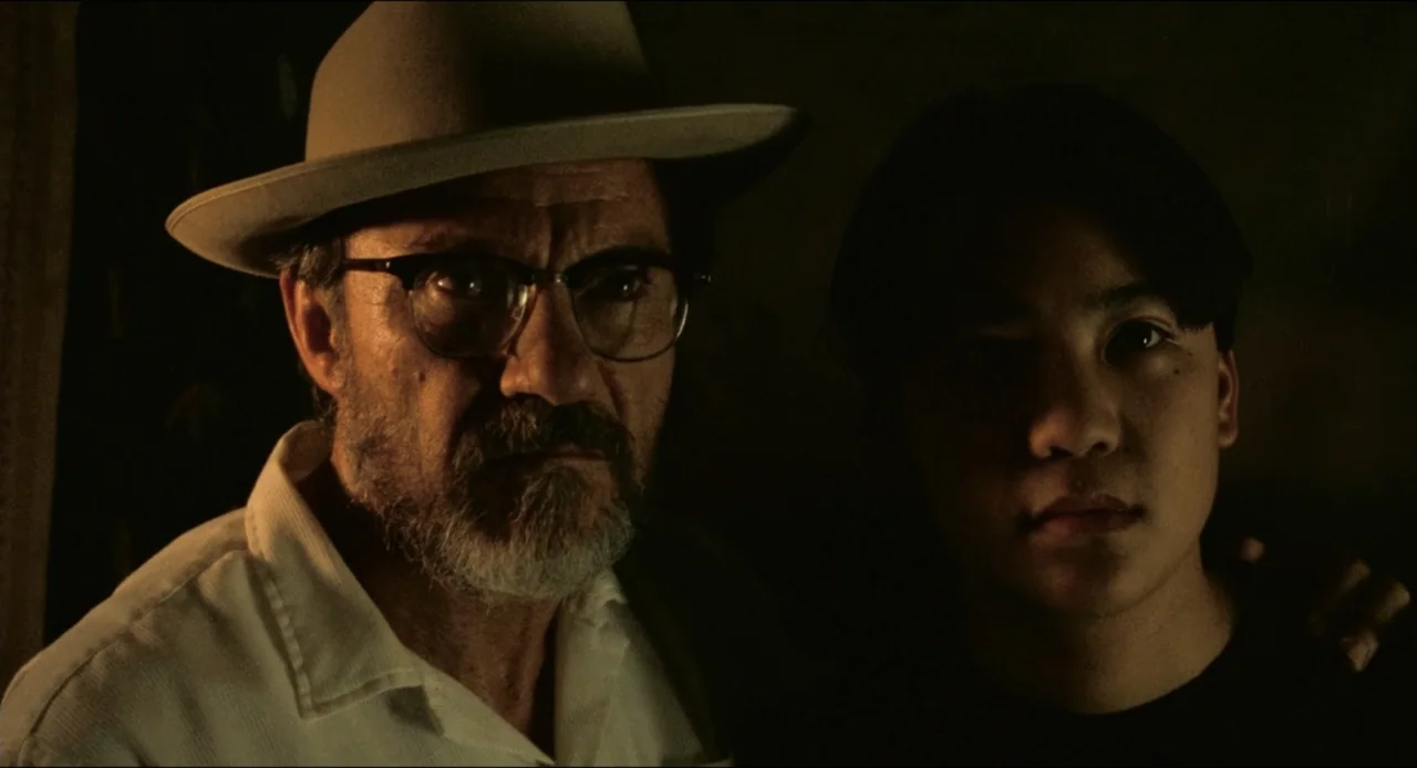 From Dusk Till Dawn (1996) movie still: medium — A dark indoor setting provides a minimalist background for the two subjects. An older man in a…