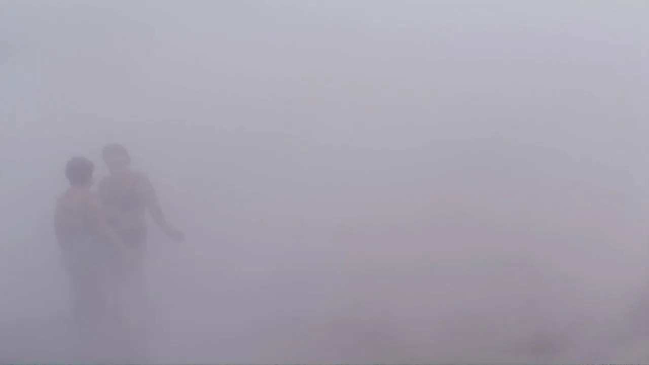 Letters to Max (2014) movie still: wide — An expanse of shoreline is shrouded in dense white fog. Two women in swimsuits stand near the water edge…