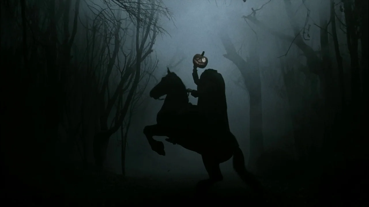 Sleepy Hollow (1999) movie still: wide — A dense dark woodland is filled with thick ground fog and bare silhouetted trees. A headless rider mounted…
