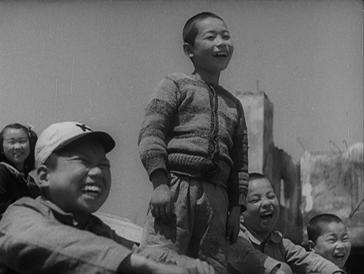Anatomy of a Relationship (1976) movie still: medium — A group of children laugh while standing in an area filled with stone rubble. The children…