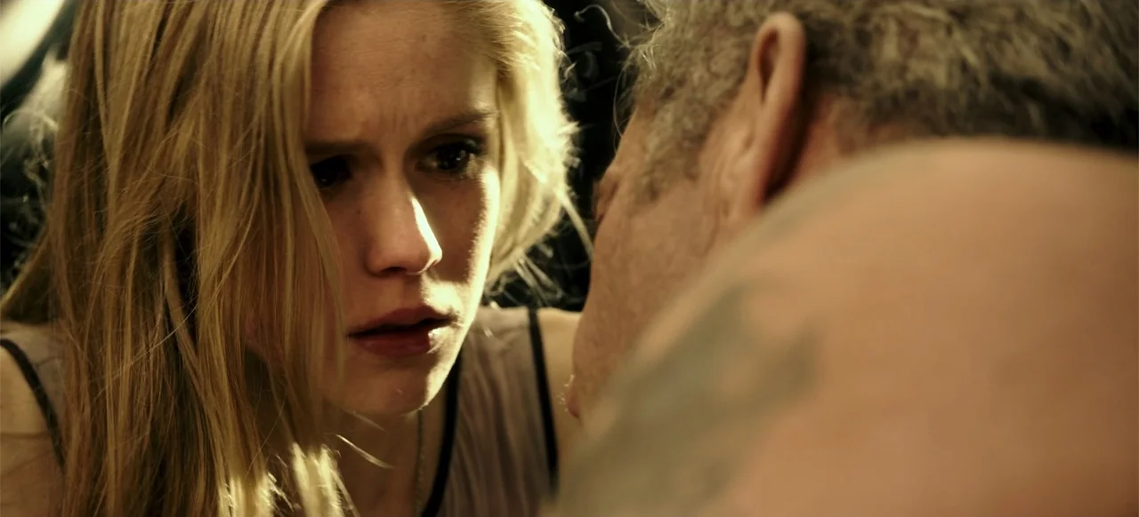 Blood Father (2016) movie still: closeup — A close-up view inside a vehicle cabin at night with low interior lighting. A young woman looks toward a…