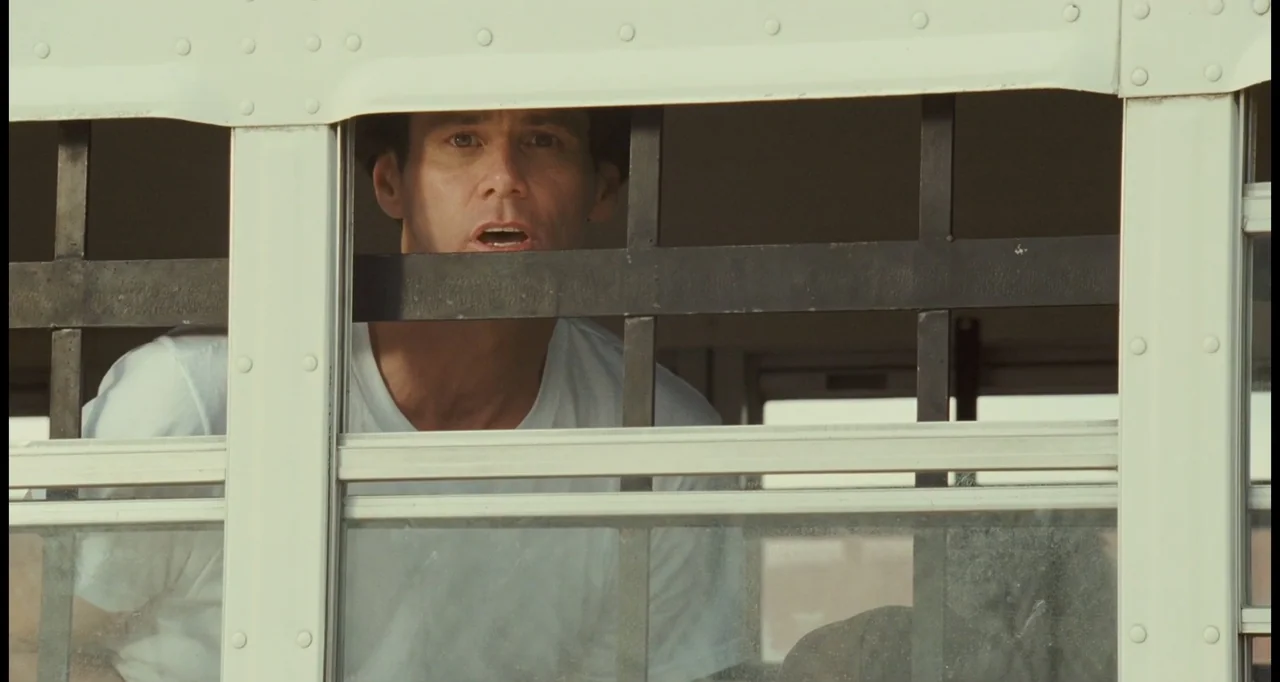 I Love You Phillip Morris (2010) movie still: closeup — A view through a white window frame with vertical black metal bars. A man wearing a white…