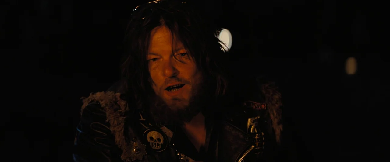 The Bikeriders (2023) movie still: closeup — A dark night setting where only the face and shoulders of a man are visible. The subject wears a…