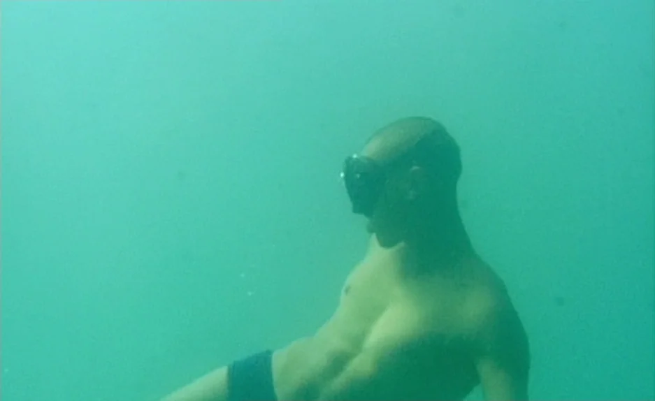 Beau Travail (1999) movie still: medium — A man swims through clear turquoise water beneath the surface. The scene is illuminated by daylight…