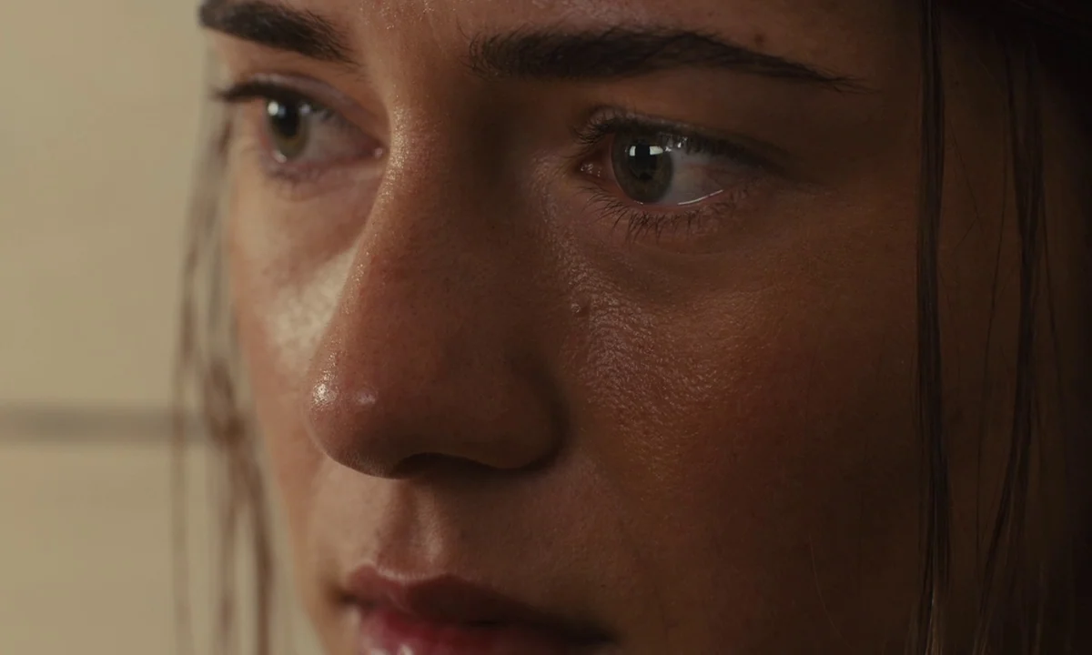 Slow West (2015) movie still: closeup — A close-up view focuses on a woman's face within an interior space. The subject stares ahead with a neutral…
