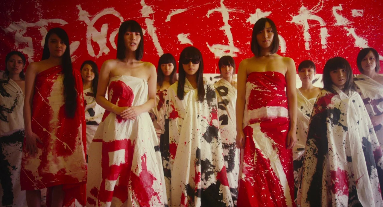 Making of: Antiporno (2016) movie still: medium — A group of women stands in front of a wall covered in red paint. They wear white fabrics splashed…