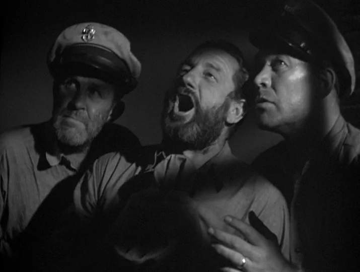 They Were Expendable (1945) movie still: medium — A dark space where three men are illuminated by a harsh, directional light source. The men stare…
