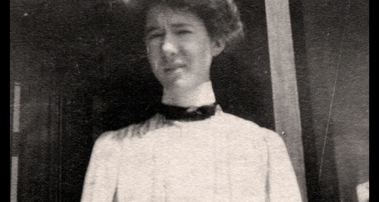 Living With Lincoln (2015) movie still: medium — A woman stands on an outdoor porch with a dark background structure behind her. She faces forward…