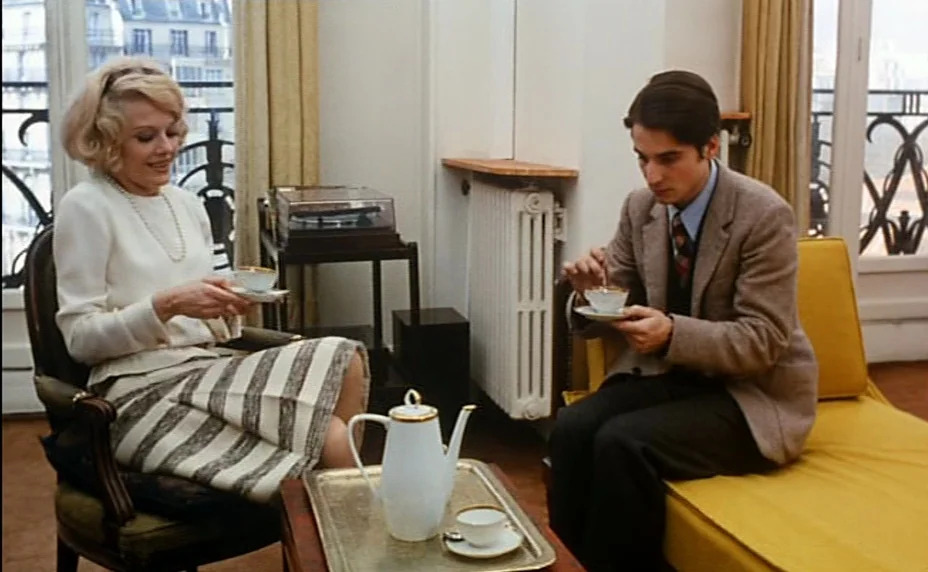 Stolen Kisses (1968) movie still: medium — A refined apartment interior with floor-to-ceiling windows and light beige curtains. A woman and a man…
