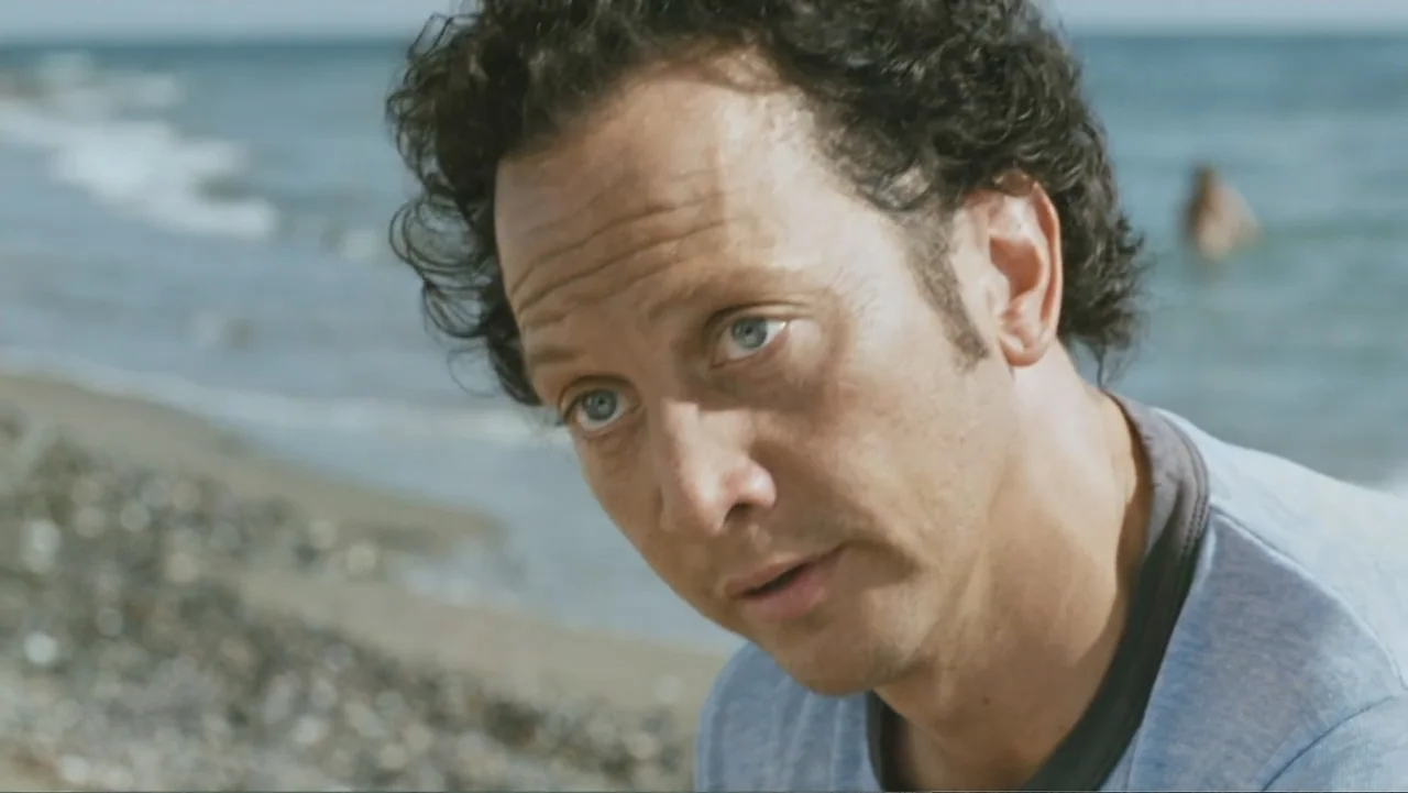 Deuce Bigalow: European Gigolo (2005) movie still: closeup — A sunny beach scene featuring shoreline and ocean in the blurred background. A man…