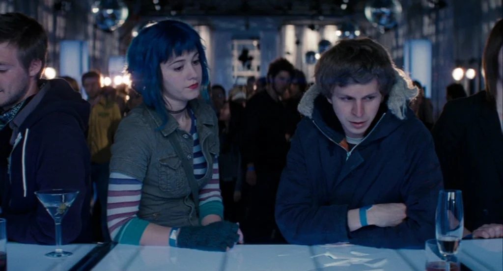 Scott Pilgrim Vs The World (2010) movie still: medium — A dimly lit club interior features a glossy white bar illuminated from below. A young woman…