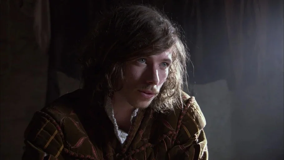 The Tudors (2007) movie still: closeup — A dimly lit stone chamber provides the backdrop for the close-up portrait of a man. The subject gazes…