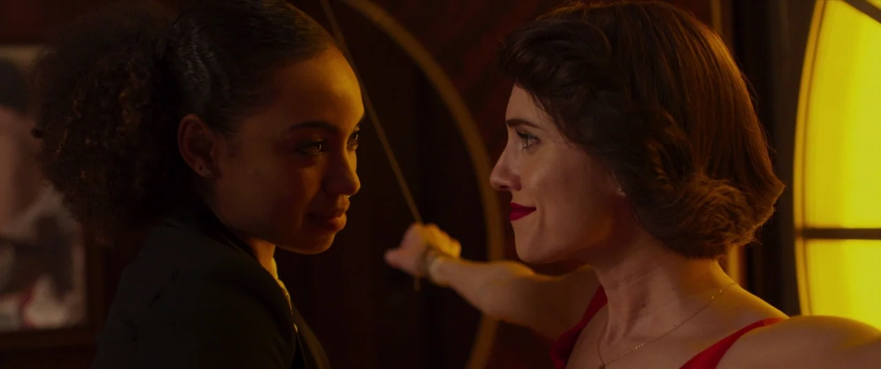 The Perfection (2018) movie still: medium — A dark dimly lit bar environment with circular yellow lighting elements in the background. Two women…