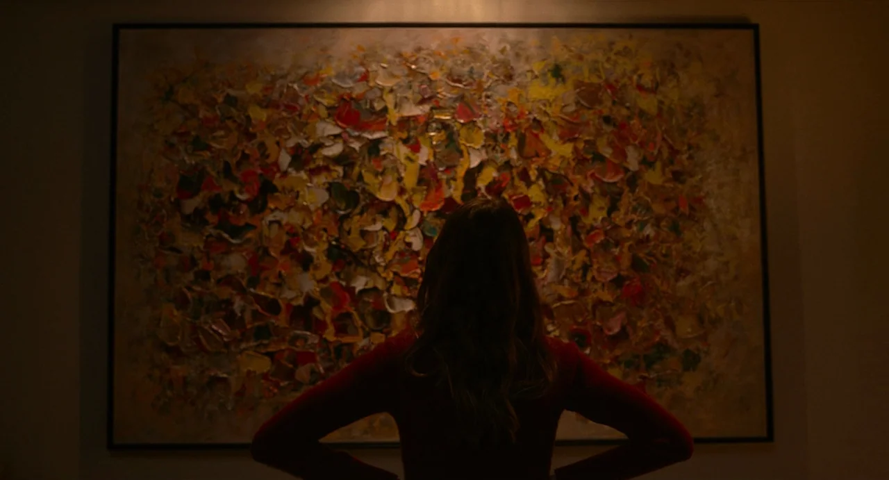 Fresh (2022) movie still: medium — A dim room features a large, heavily textured oil painting with yellow and red impasto. A woman in a red sweater…