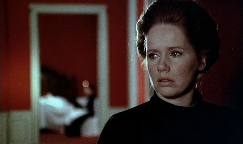 Cries and Whispers (1972) movie still: closeup — A woman stands in a room with vibrant red walls and white door frames. She turns her head slightly…