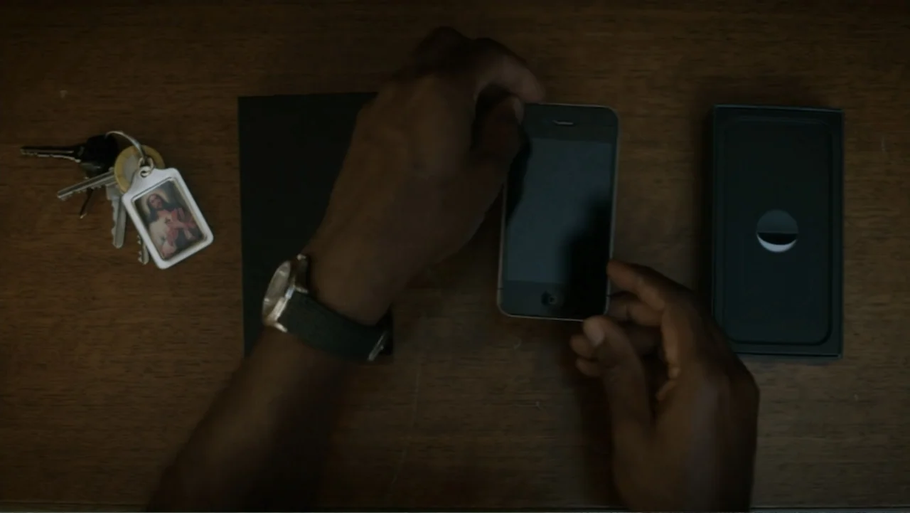 Nightingale (2014) movie still: closeup — A dark-toned wooden table features a set of keys with a religious pendant.