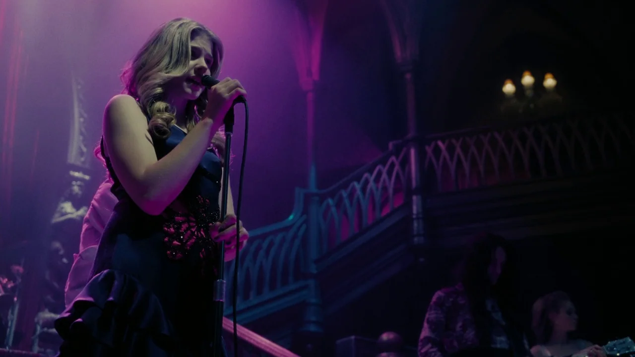 Dark Shadows (2012) movie still: medium — A dimly lit indoor concert venue features ornate dark wood railings and balconies. A young woman with…
