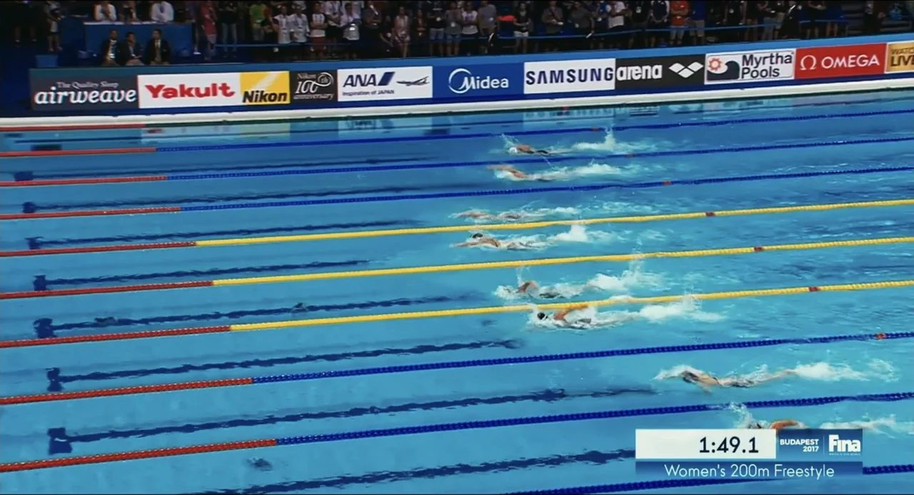 Federica Pellegrini - Underwater (2022) movie still: wide — An Olympic-sized outdoor swimming pool features multiple lanes with several competitive…