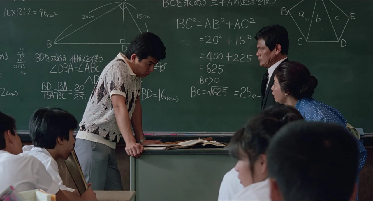 Typhoon Club (1985) movie still: medium — A classroom features a green chalkboard covered in handwritten geometry equations and diagrams. Three…