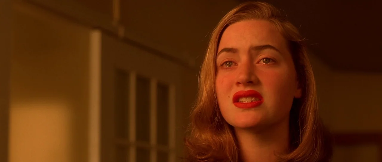 Heavenly Creatures (1994) movie still: closeup — A dimly lit room with an out-of-focus doorway in the background. A woman with light brown hair…