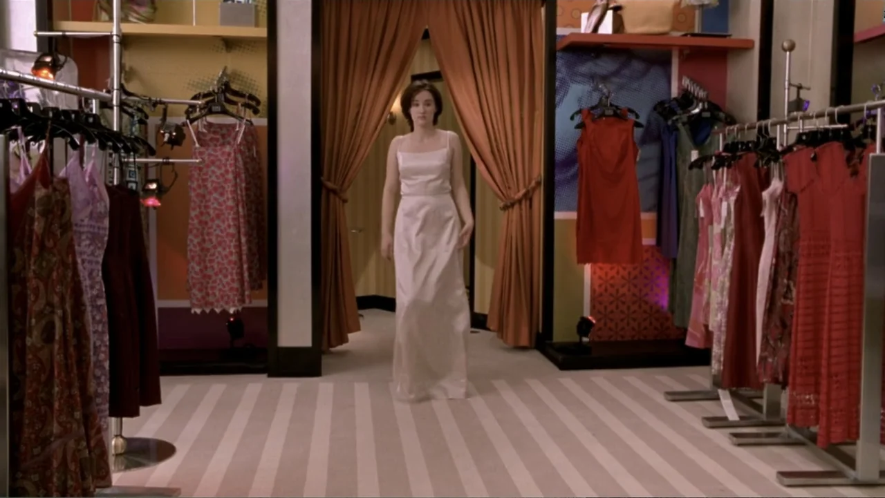 What Women Want (2000) movie still: fullbody — A retail clothing boutique features racks of garments under bright interior lighting. A young woman…