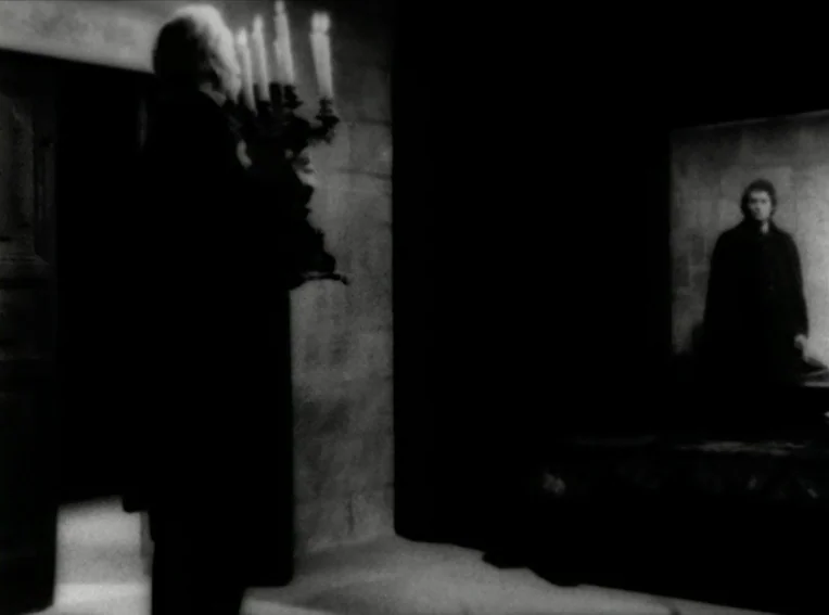Cuadecuc, Vampir (1971) movie still: wide — A dark stone interior features a man in the foreground carrying a candelabra. Further back, another man…