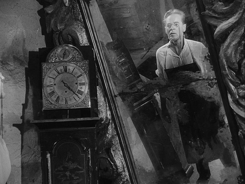 The Magician (1958) movie still: medium — A dimly lit room contains an antique tall case clock beside a large mirror. A thin, older man stares at…