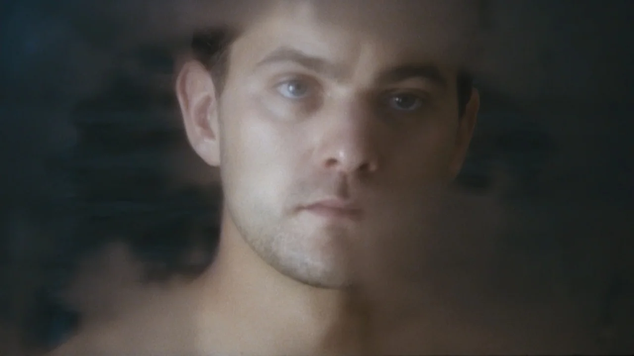 Shadows in the Sun (2005) movie still: closeup — A close-up view shows a man's face framed within a bathroom environment. The subject looks directly…