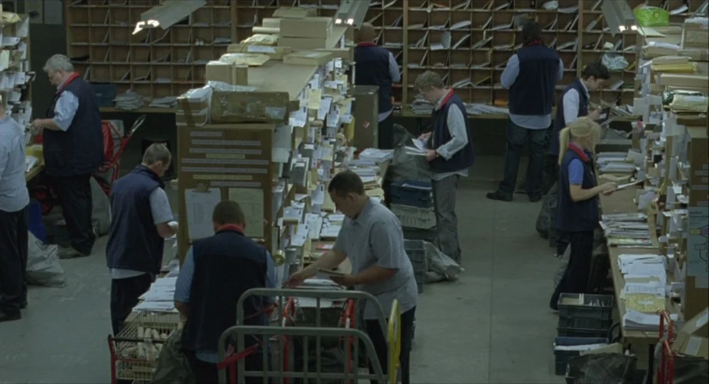 Looking for Eric (2009) movie still: wide — A large postal sorting center filled with tall wooden shelves containing many mail compartments.…