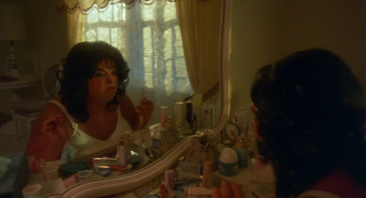 Polyester (1981) movie still: medium — A cluttered vanity table sits in front of a window covered by yellow curtains. A person with dark hair…