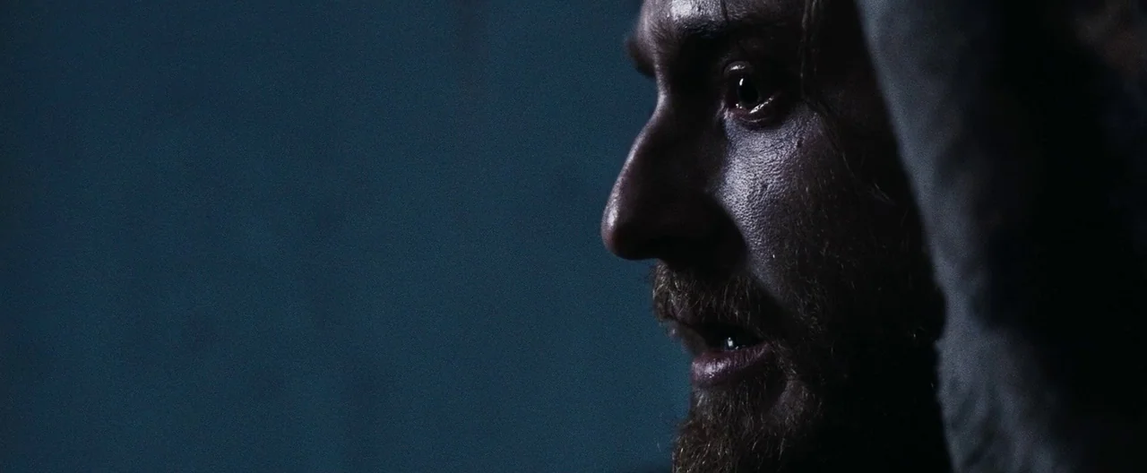 30 Days of Night (2007) movie still: closeup — A dark, undefined interior space creates a backdrop for a close-up facial study. A man with a beard…