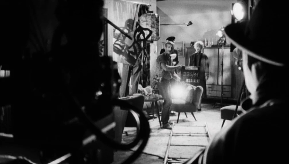 Veronika Voss (1982) movie still: medium — A film production set featuring crew members and professional lighting equipment indoors. A man holds a…