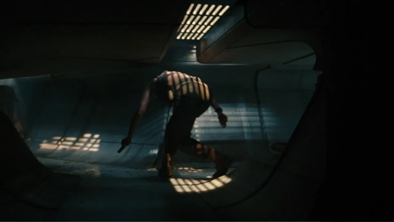 Jurassic World Rebirth (2025) movie still: medium — A metallic interior corridor features curved walls and overhead light filtering through iron…