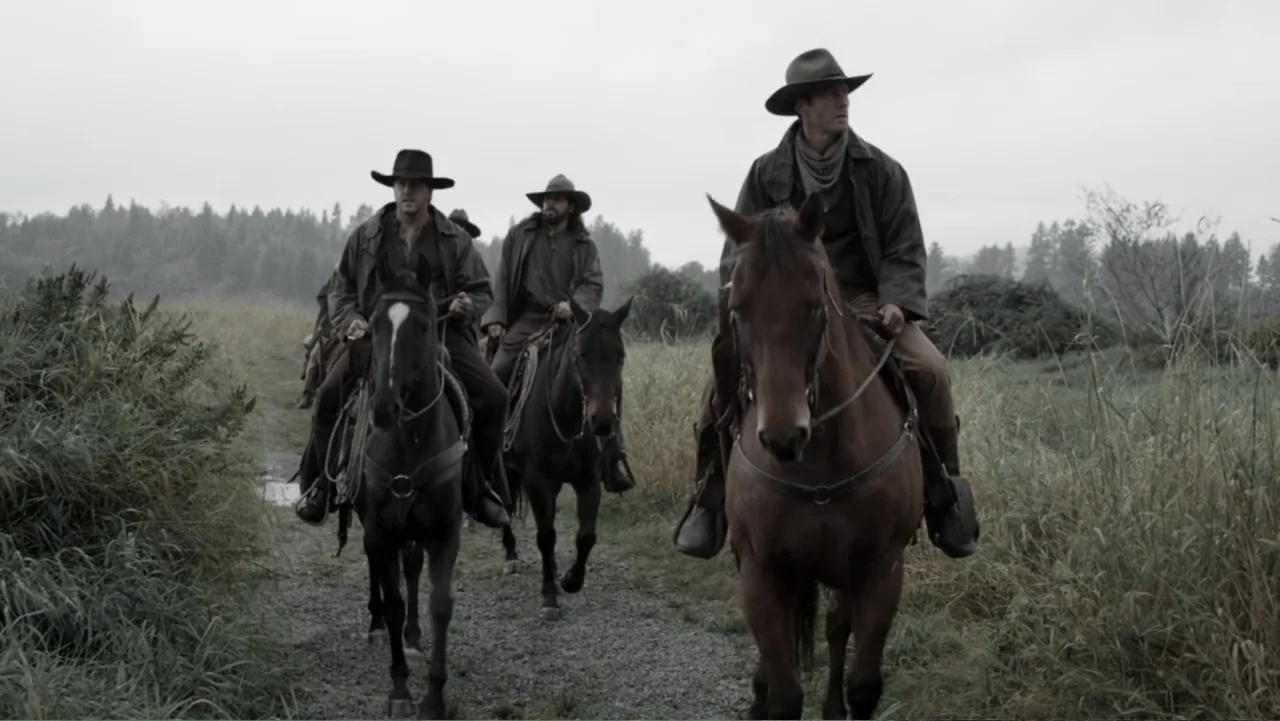 Dawn Rider (2012) movie still: fullbody — Three men on horseback ride slowly along a gravel path through a flat field. Tall grass and sparse trees…