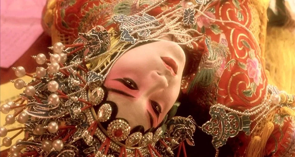 Farewell My Concubine (1993) movie still: closeup — A close up of a person wearing traditional Beijing Opera makeup and an ornate headpiece. They…
