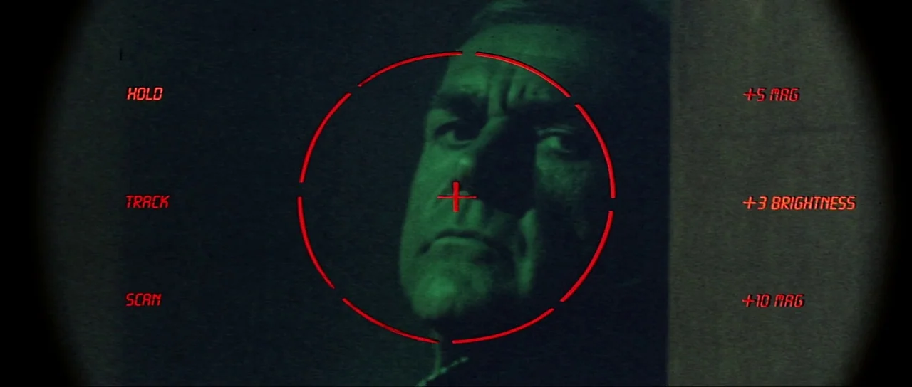Never Say Never Again (1983) movie still: closeup — A digital surveillance monitor displays a close-up view of a man in green light. The frame is…