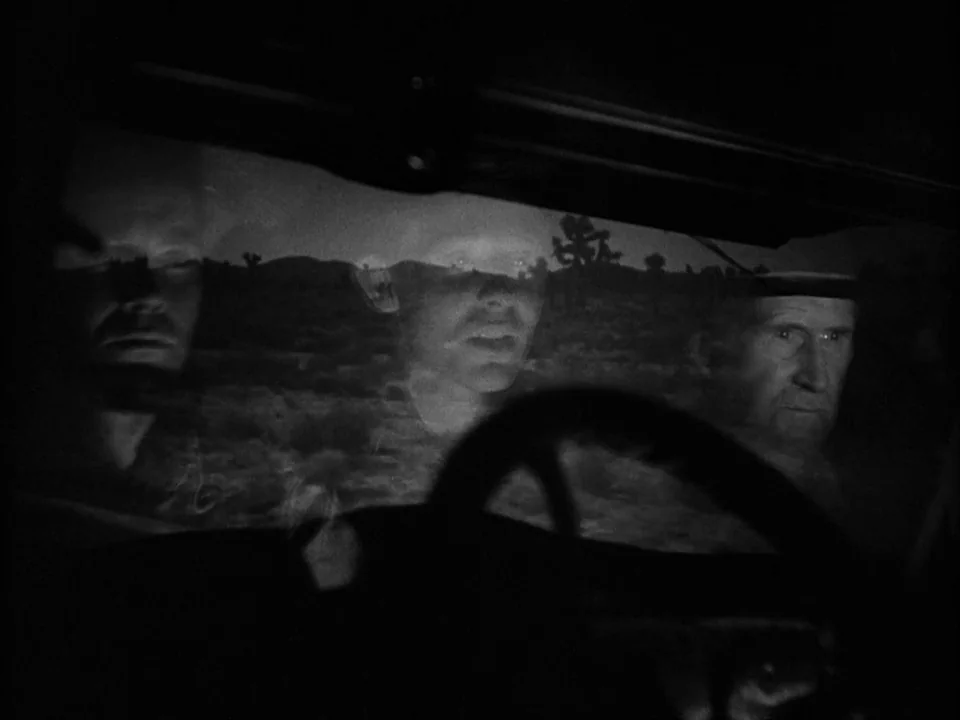 The Grapes of Wrath (1940) movie still: medium — Three men are visible through a car windshield against a dark desert landscape. Their faces appear…