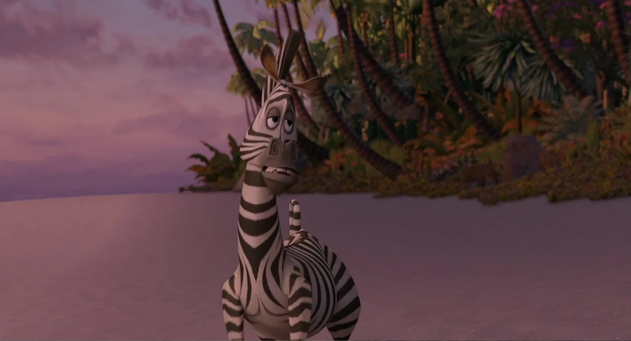 Madagascar (2005) movie still: fullbody — A sandy beach meets a dense wall of tropical trees at dusk. A lone zebra stands on the beach while looking…